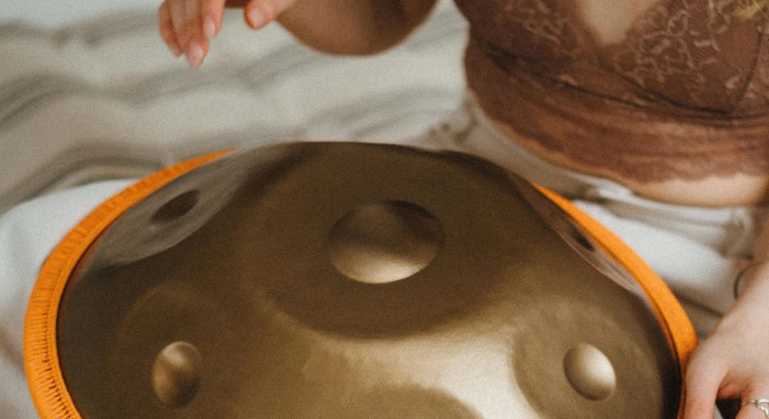 Close-up of a woman playing a bronze-colored handpan