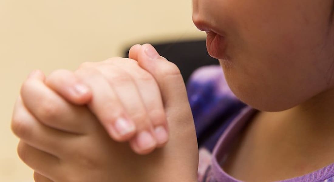 A girl blowing into her hands like an ocarina