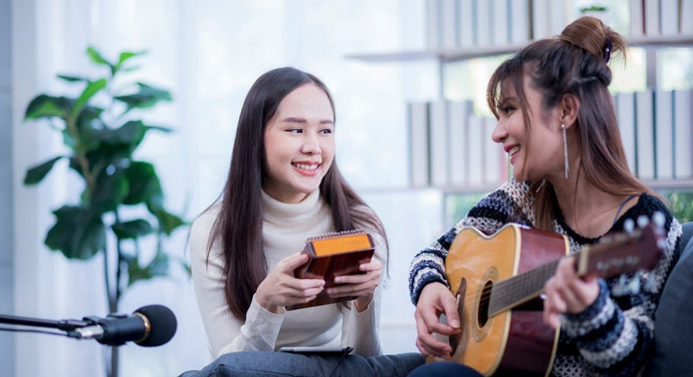 A girl playing a kalimba while her mother plays guitar