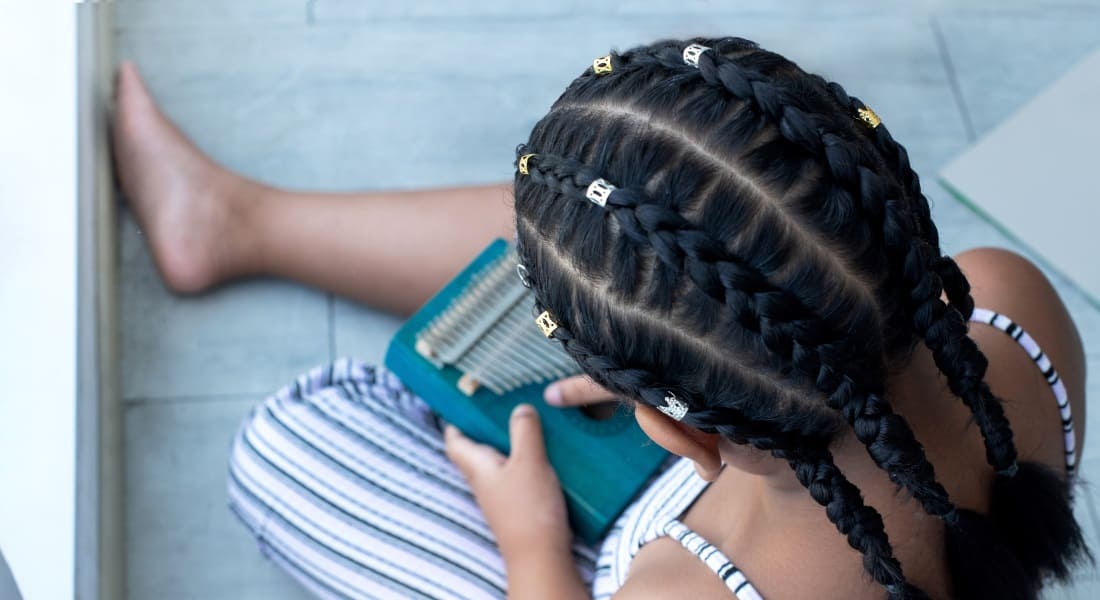 A girl seen from above playing a kalimba