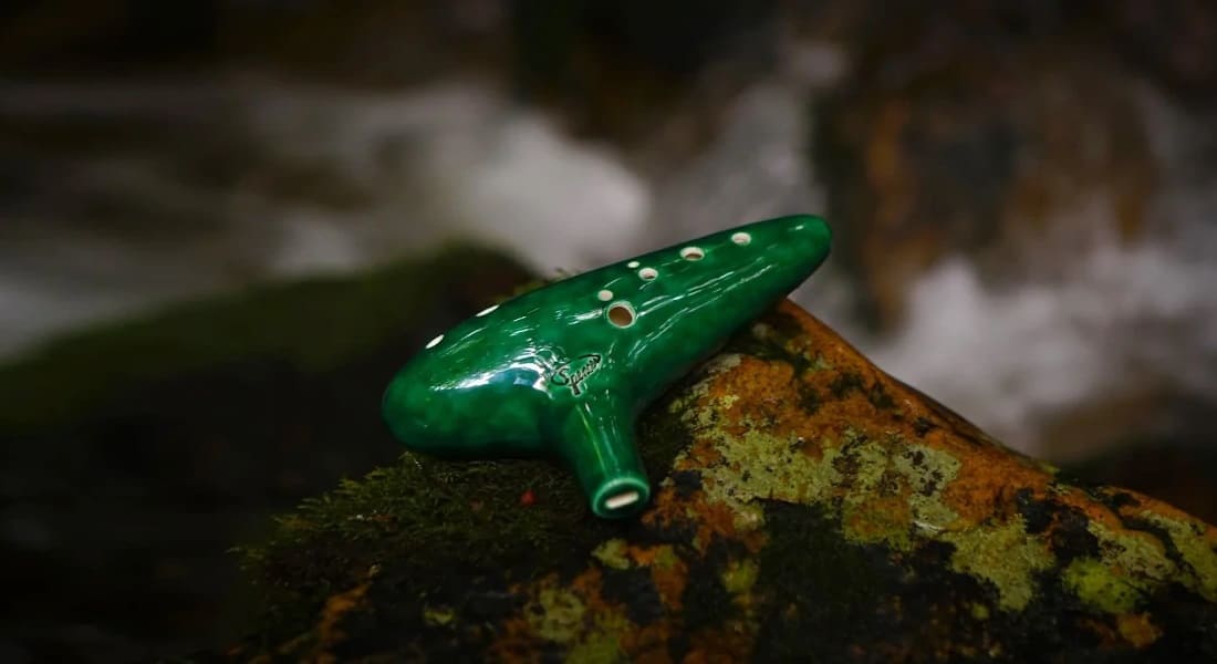 A green ocarina resting on a rock