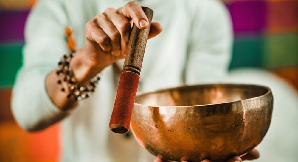 One hand holding a stick and the other holding a Tibetan singing bowl