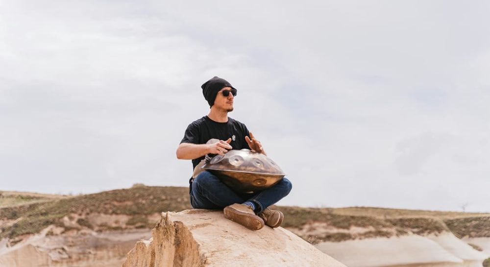 A handpan percussionist sitting in nature