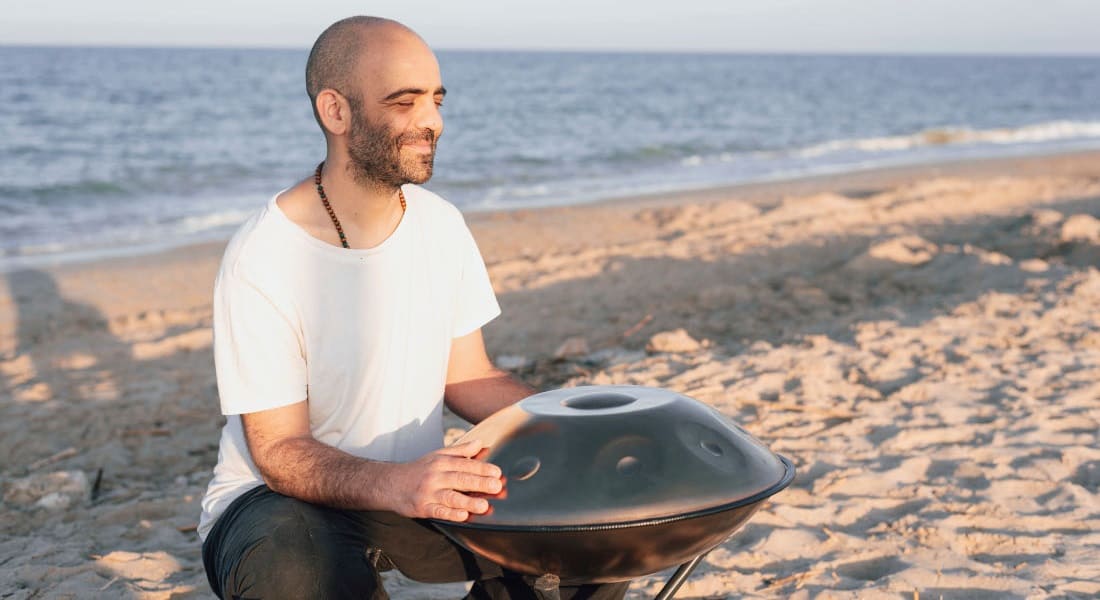 A handpan player on the beach
