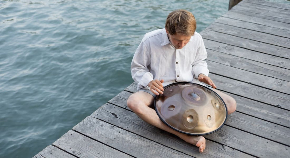A handpan player sitting on a dock