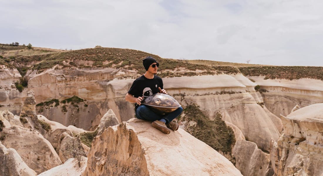 Handpan player sitting on a rock