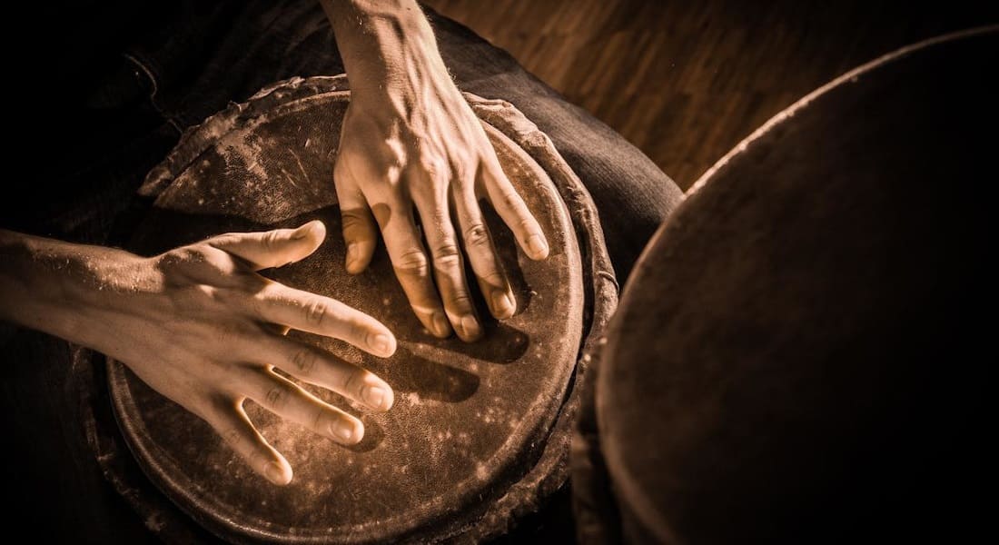 Hands striking the head of a djembe