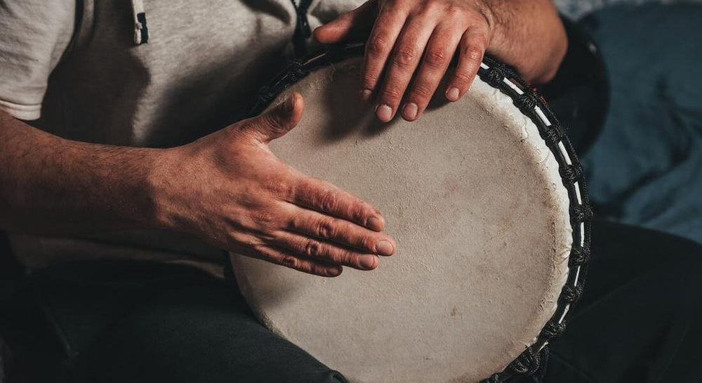 A man's hands playing djembe