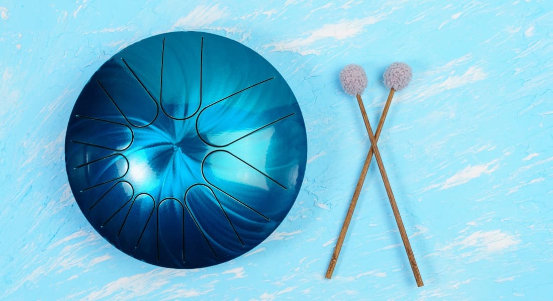 An iridescent blue tongue drum with drumsticks