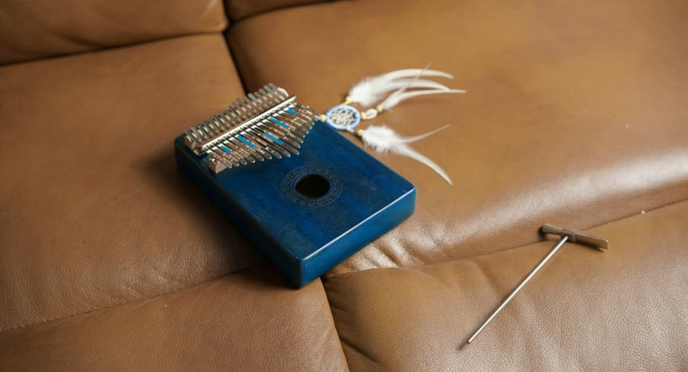 A kalimba and its tuning hammer on a couch