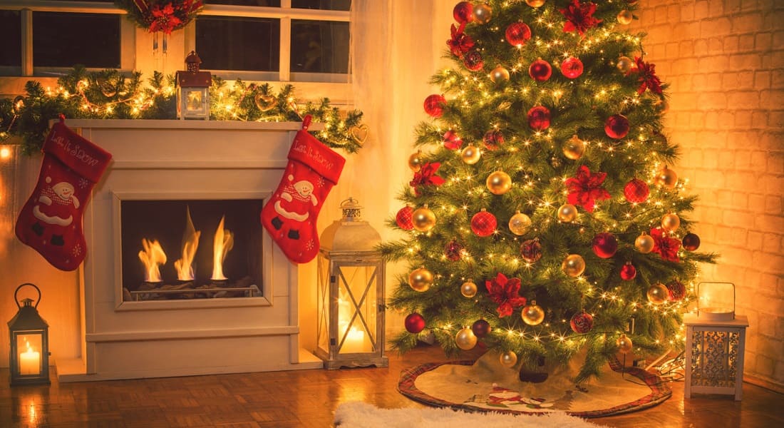 A living room decorated for Christmas with a tree and a fireplace