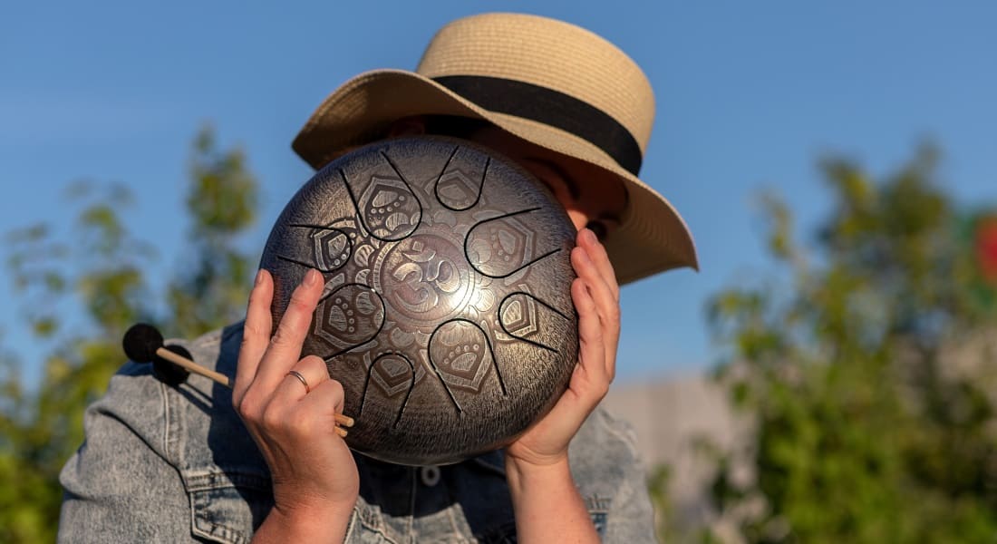 A man hiding his face behind a tongue drum