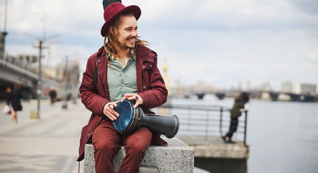 Man in a red jacket playing a djembe