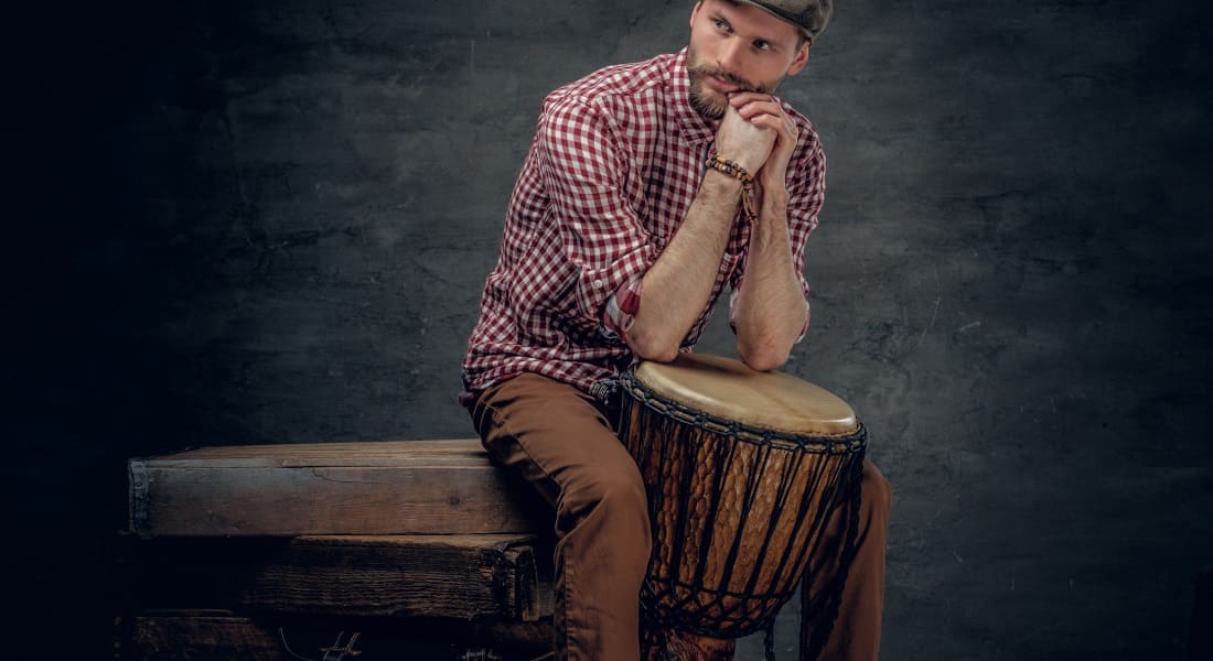 A man leaning on an engraved djembe