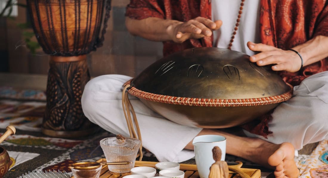 A man sitting cross-legged playing a zen drum