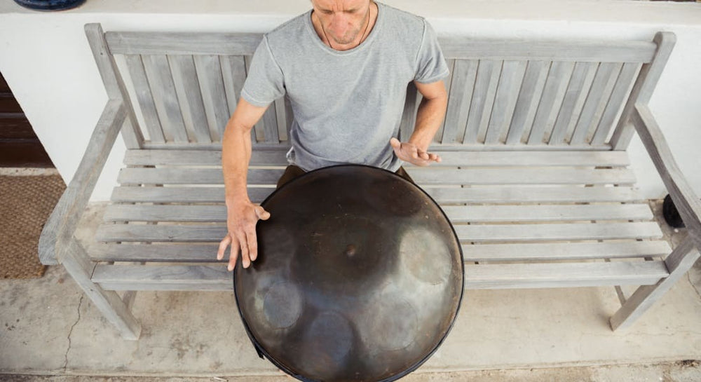 A man sitting on a bench with a handpan