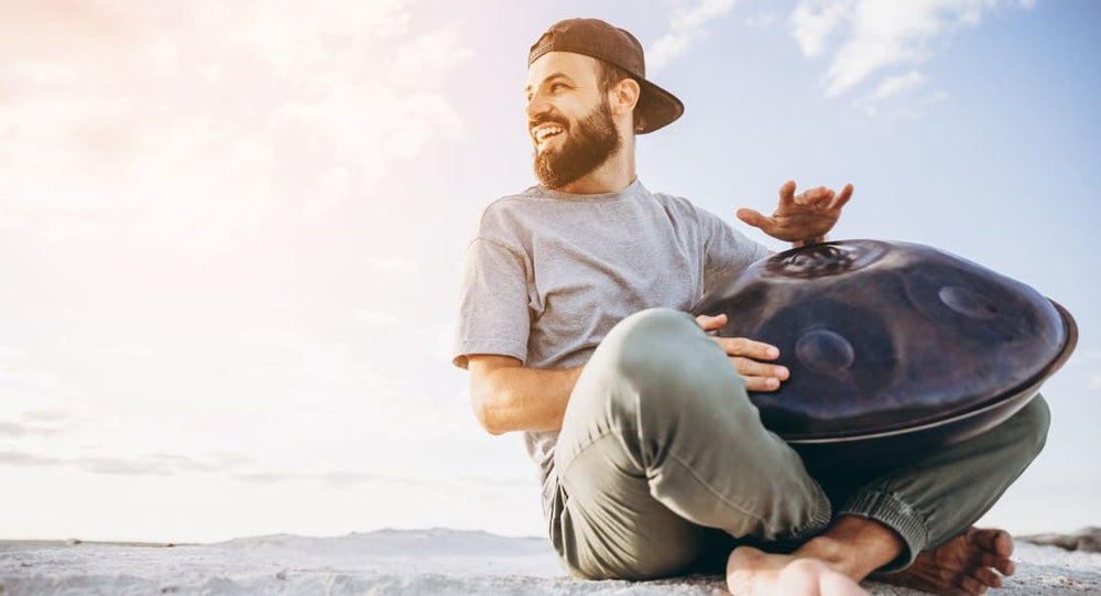 A man sitting on the ground playing a Hang