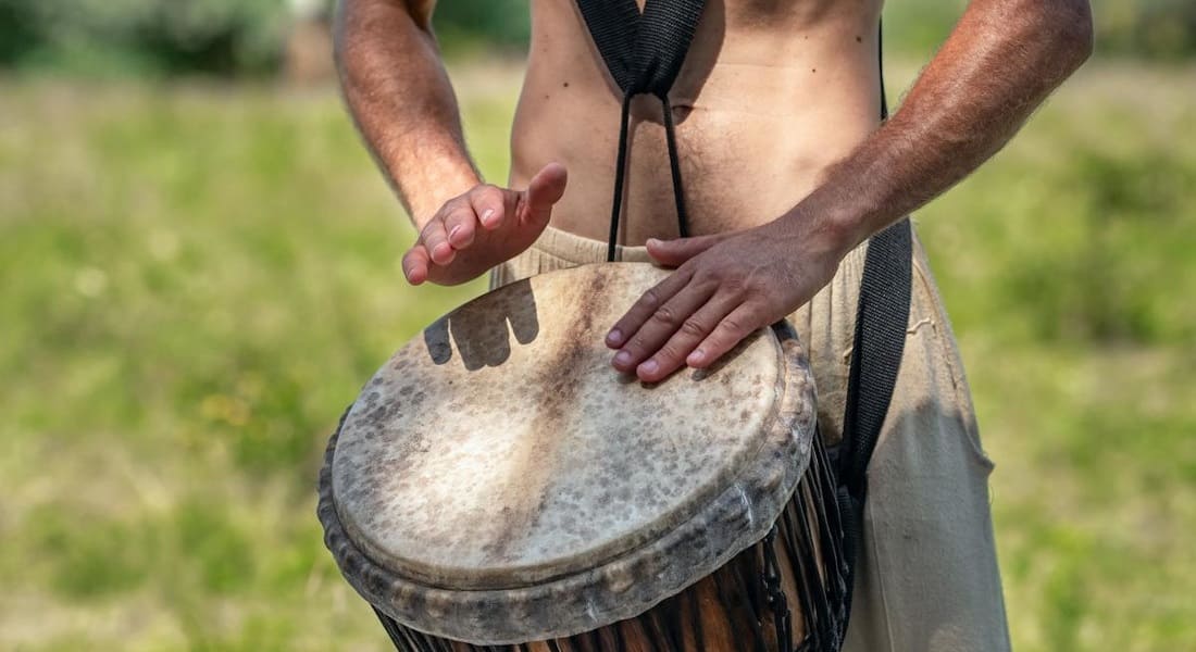 A man standing with a djembe attached to a strap