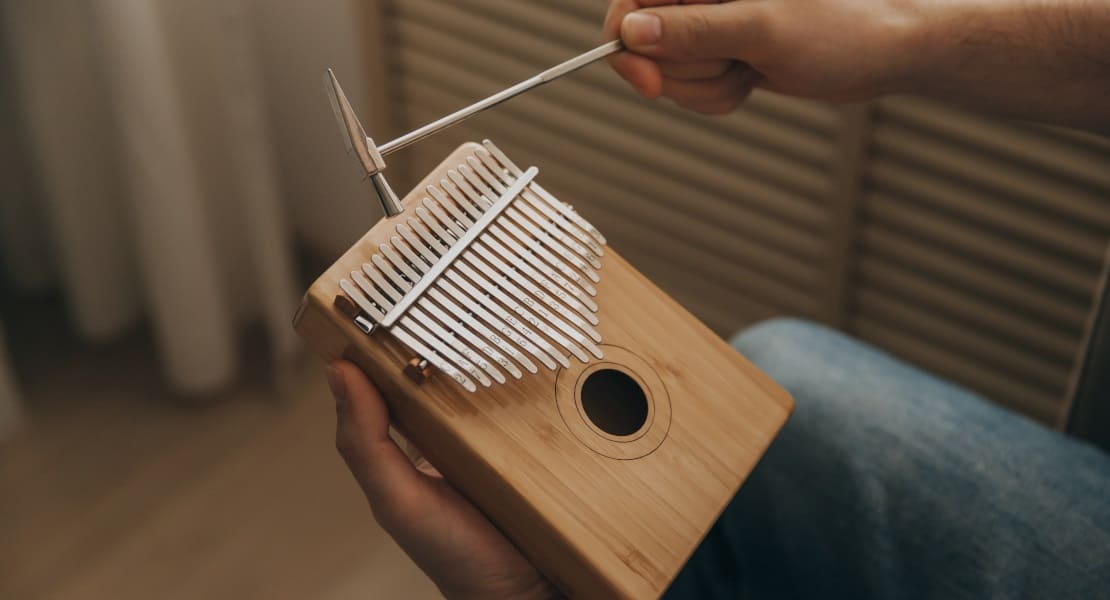 A man tuning a wooden kalimba with a hammer