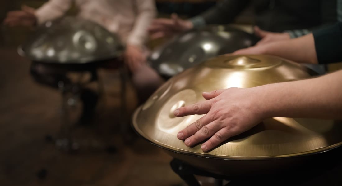 Several musicians playing handpan on a stand