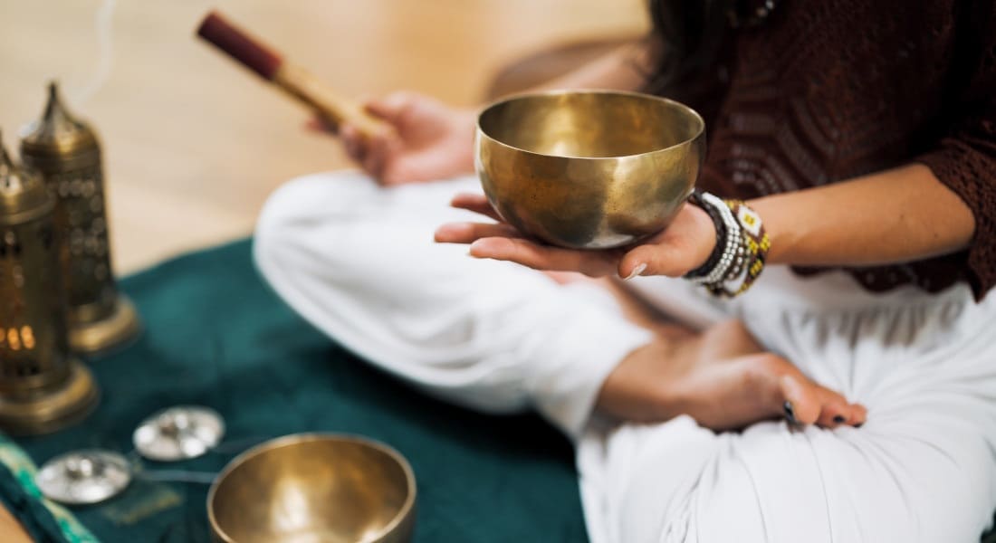A person in the lotus position with a Tibetan bowl
