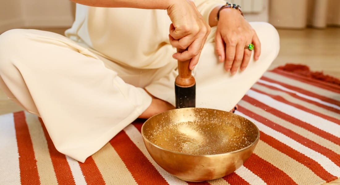 A person rubbing a singing bowl filled with water.