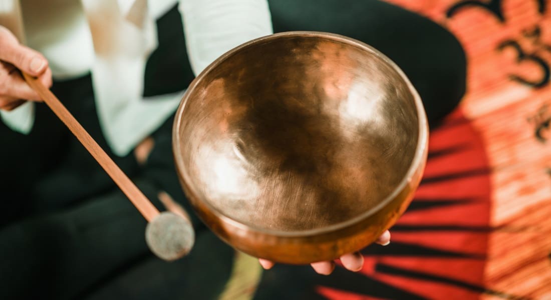 A person striking a singing bowl with a mallet