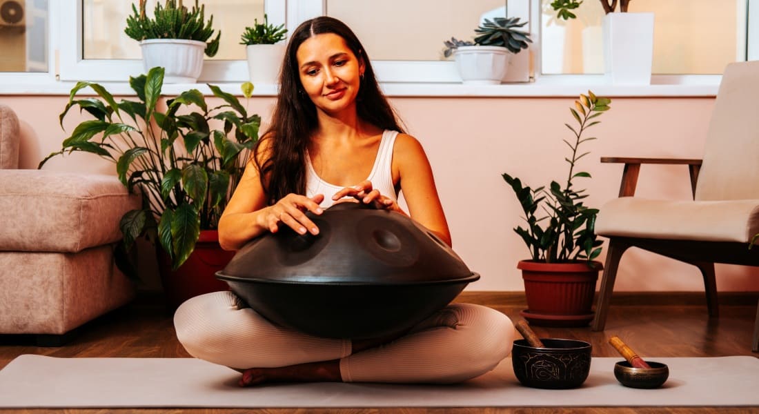 A pretty woman with a handpan between her legs