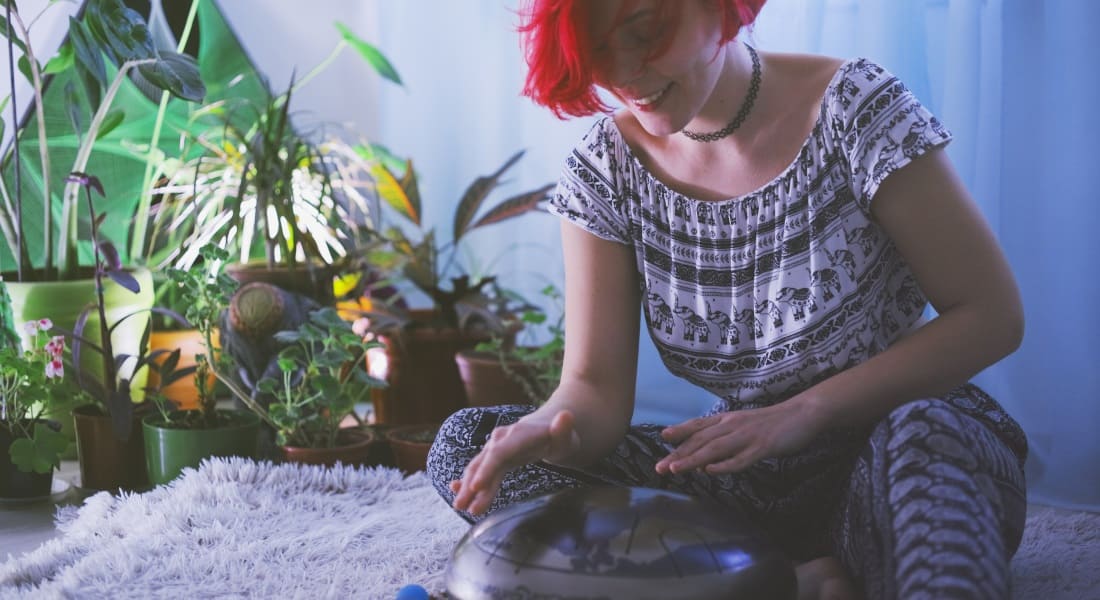 A red-haired woman playing the tongue drum with her hands