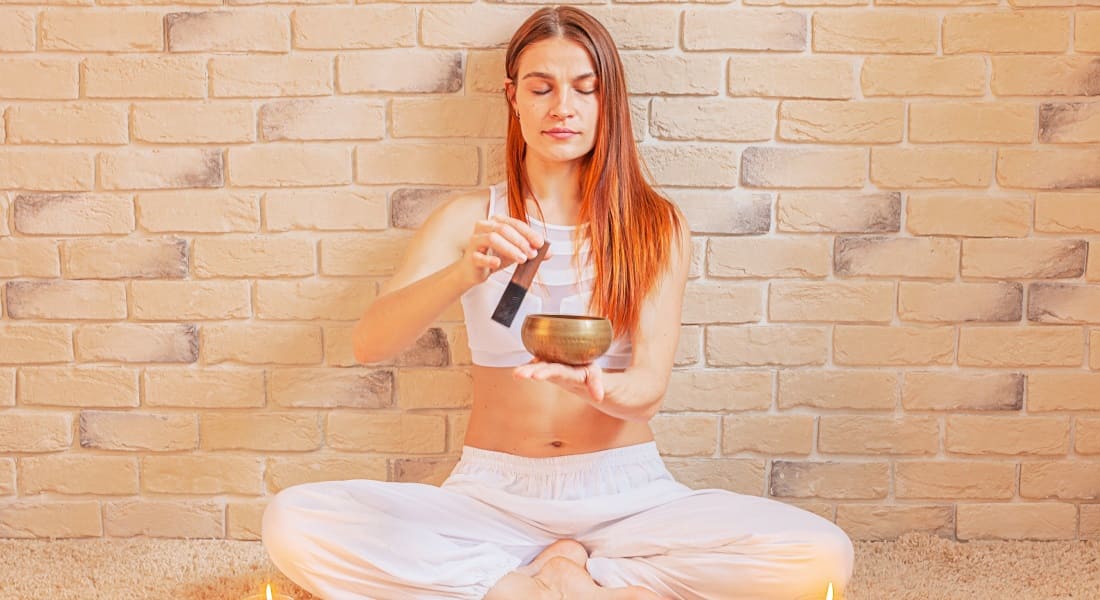 A redheaded woman relaxing with a singing bowl