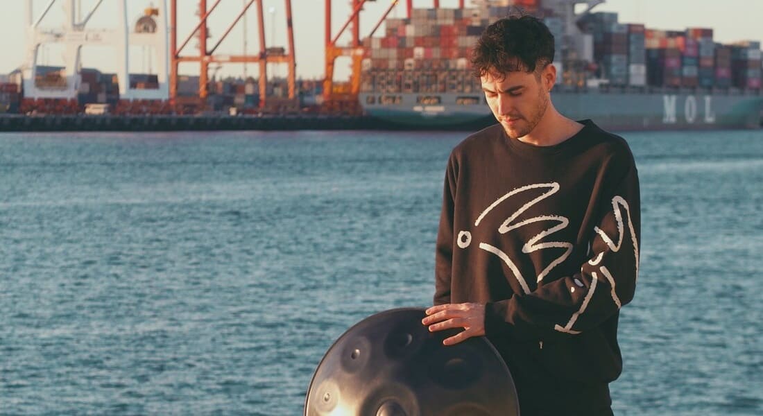 Sam Maher with a handpan at a harbor