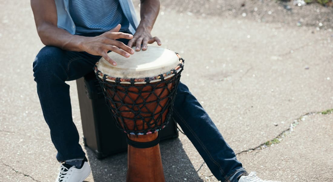 A seated man playing a djembe on the floor
