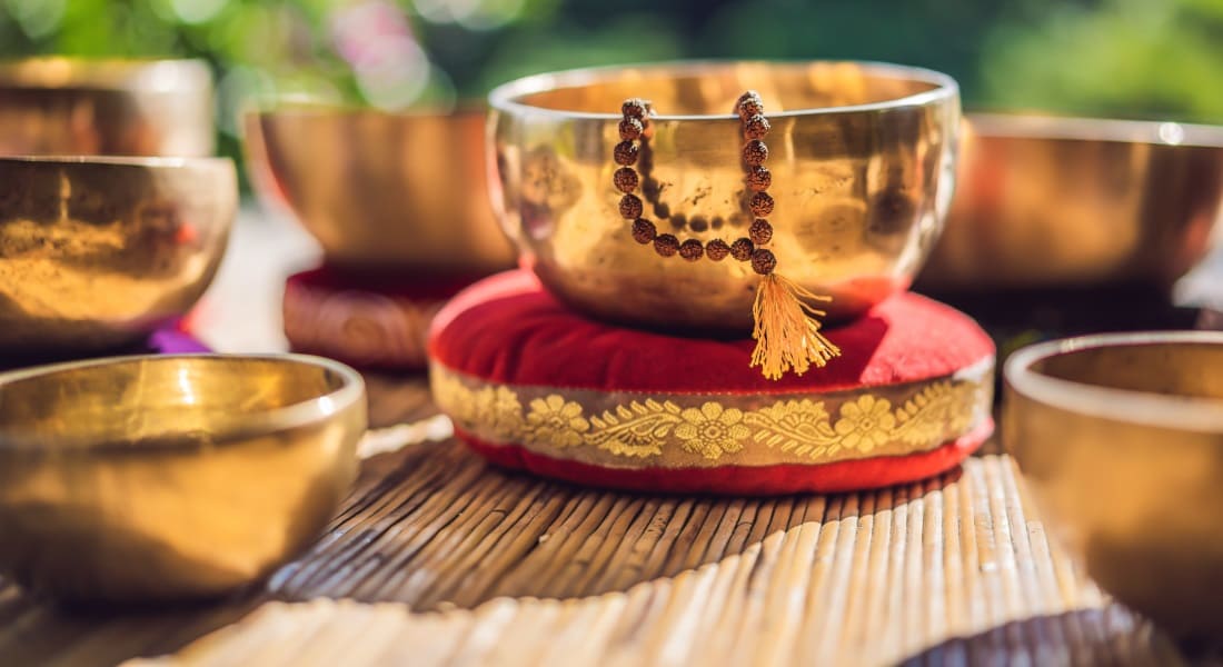 Several Tibetan singing bowls on a slatted mat