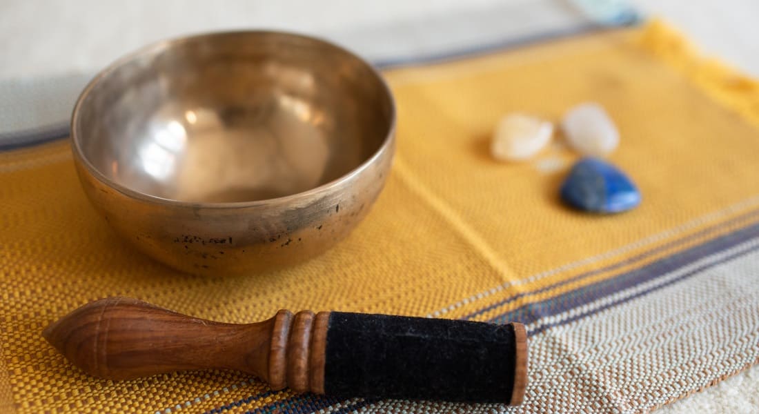 A singing bowl and a mallet on a table