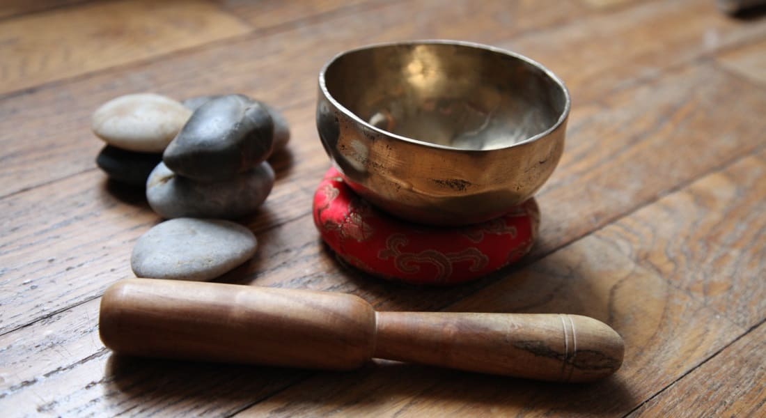 A singing bowl on a table with stones next to it