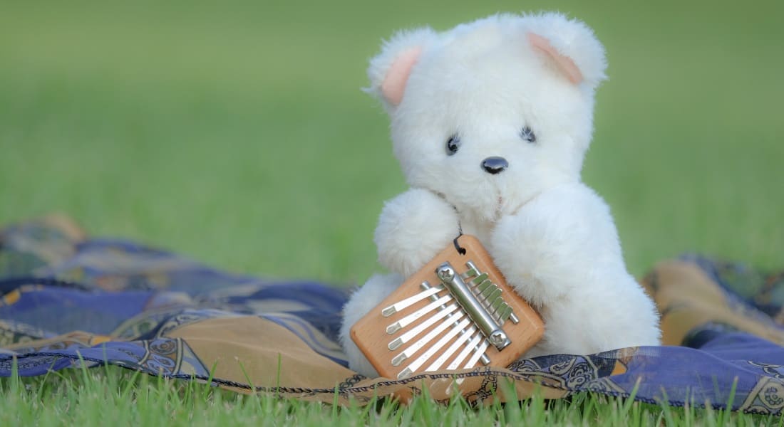 A teddy bear holding a small 8-key kalimba