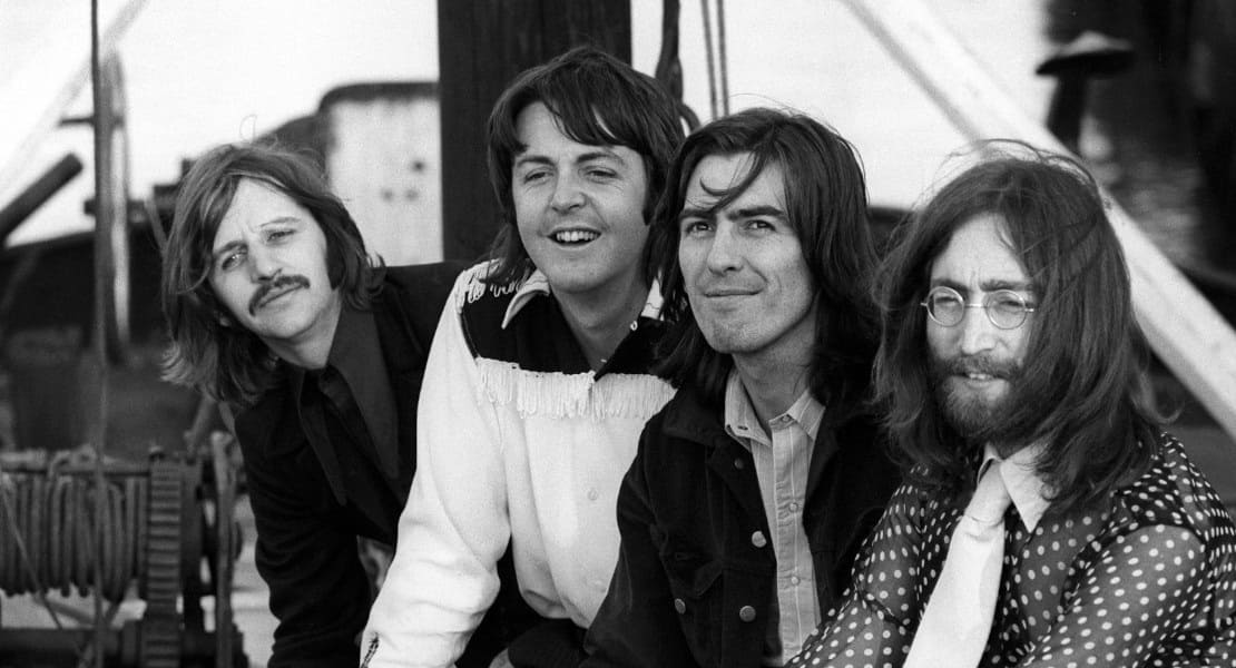The Beatles sitting and smiling