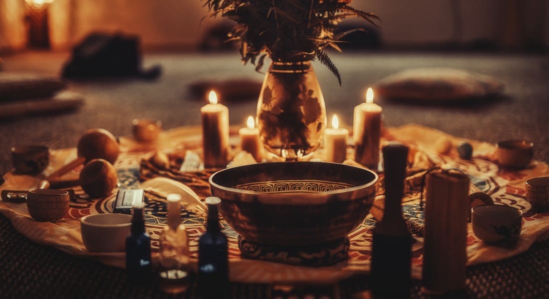 A Tibetan singing bowl surrounded by candles in the dark