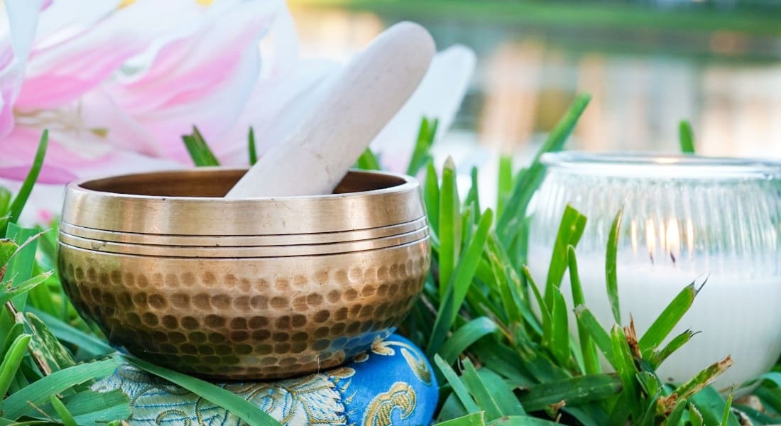 A Tibetan singing bowl and a candle in the grass