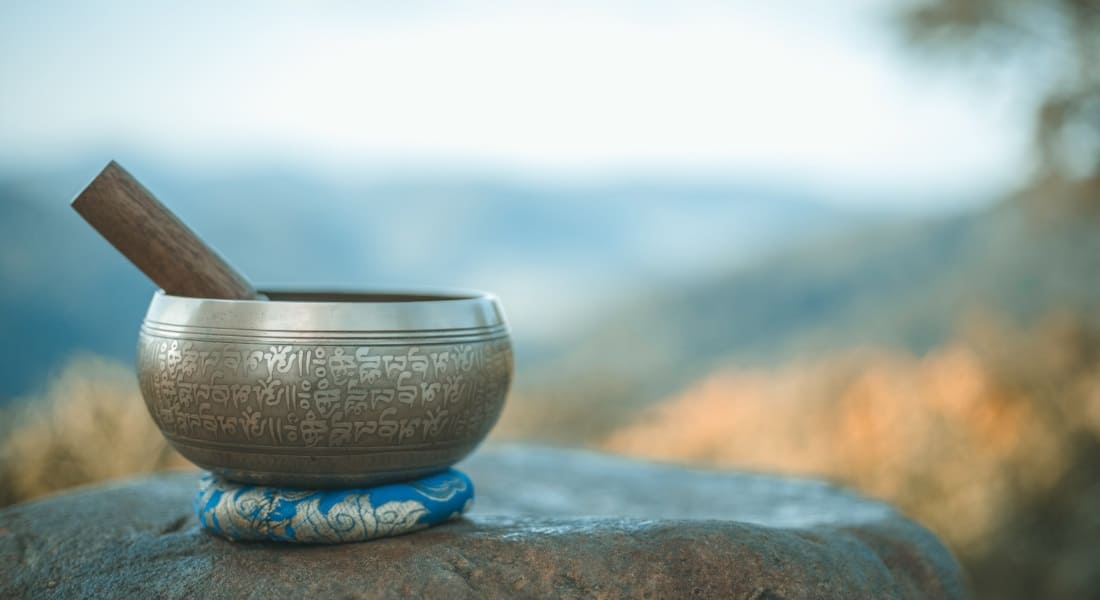 A Tibetan singing bowl placed on its blue cushion in nature