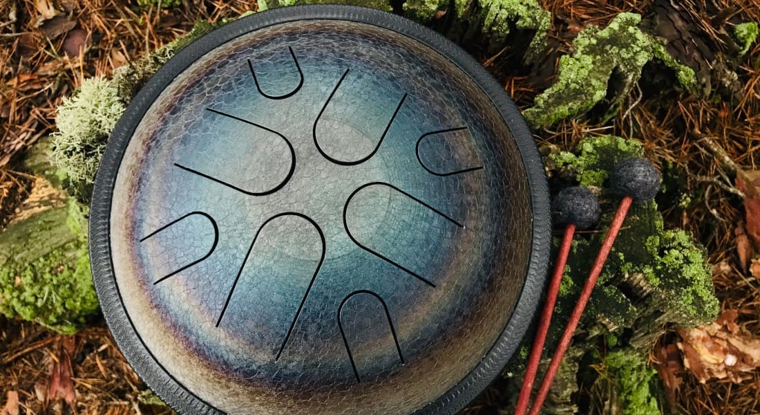 An 8-note tongue drum on the floor with mallets
