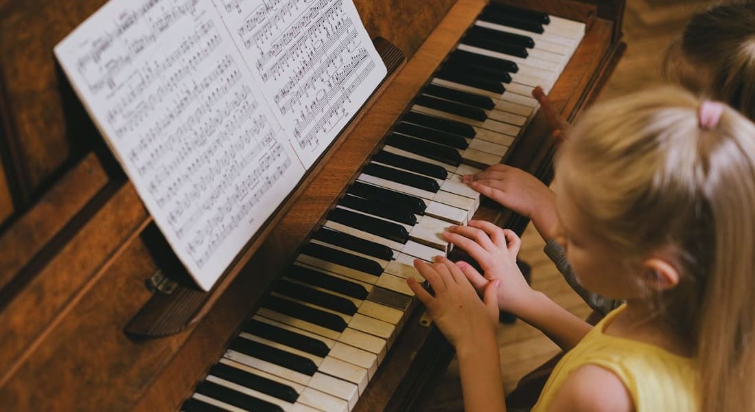 Two girls playing from sheet music at the piano