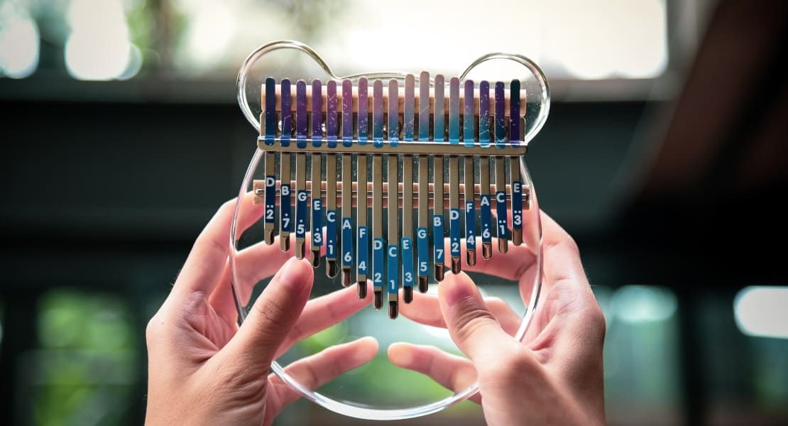 Two hands holding an acrylic glass kalimba