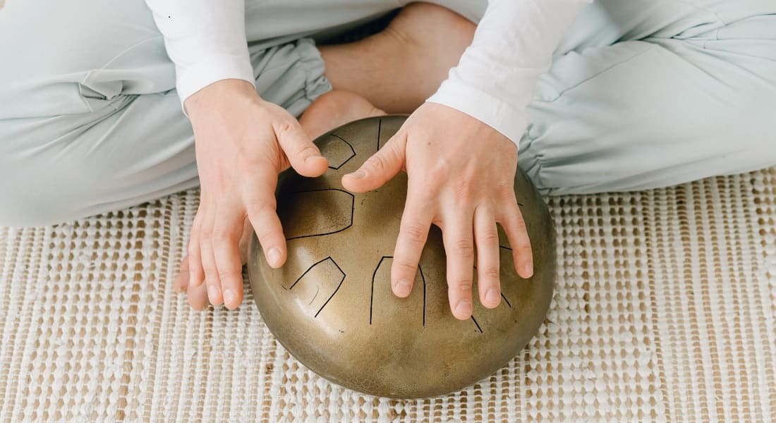 Two hands playing a gold tongue drum