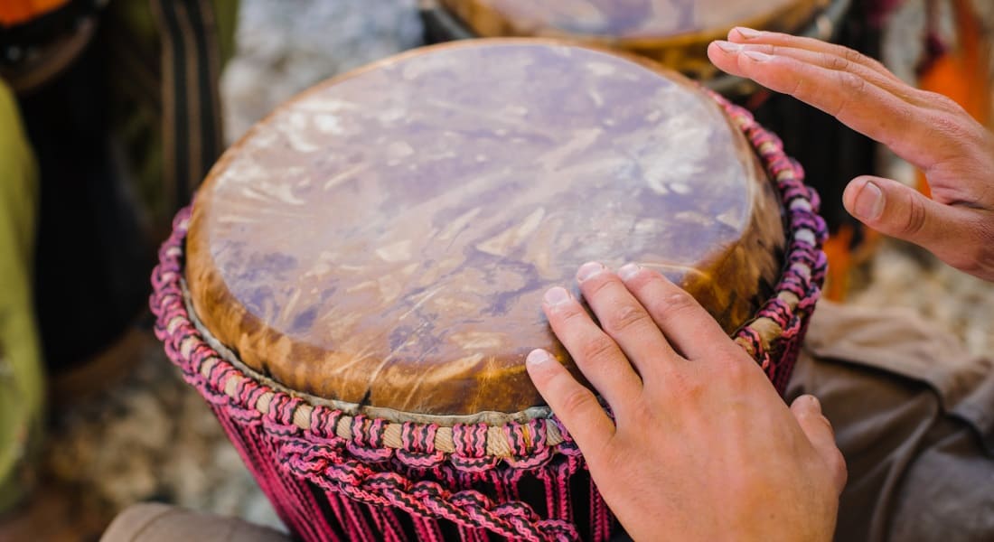 Two hands striking a handmade djembe