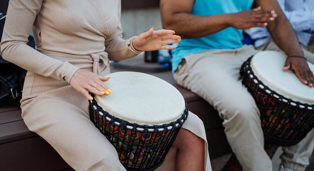Two people playing an African drum