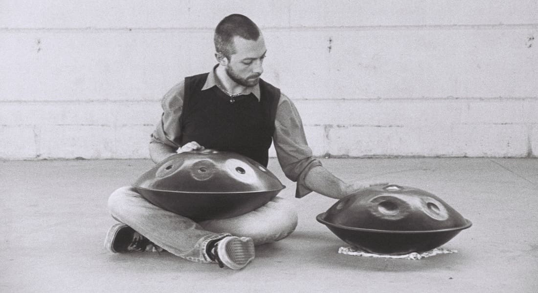 Valerio Menon seated playing two handpans