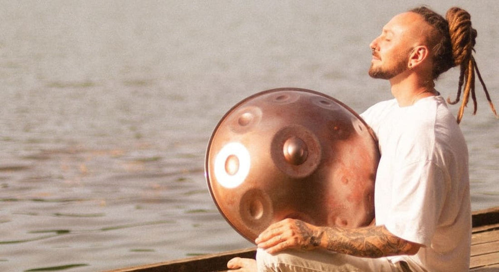 Warren Shanti meditating with a handpan by the water