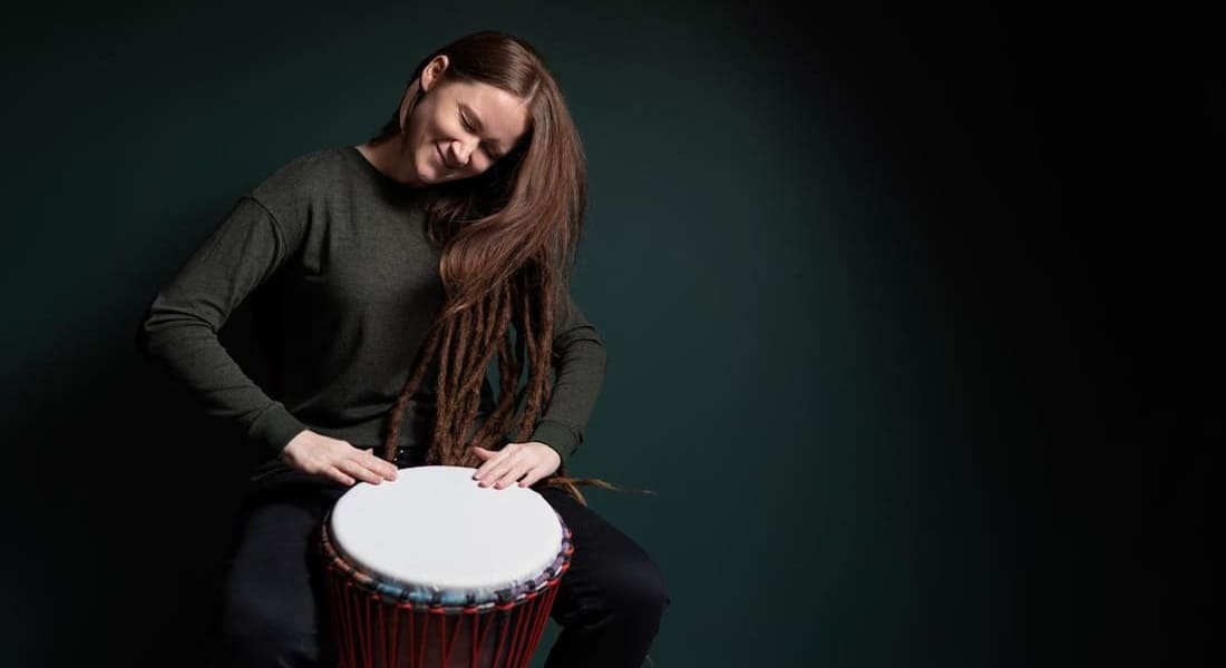 A woman enjoying playing the djembe
