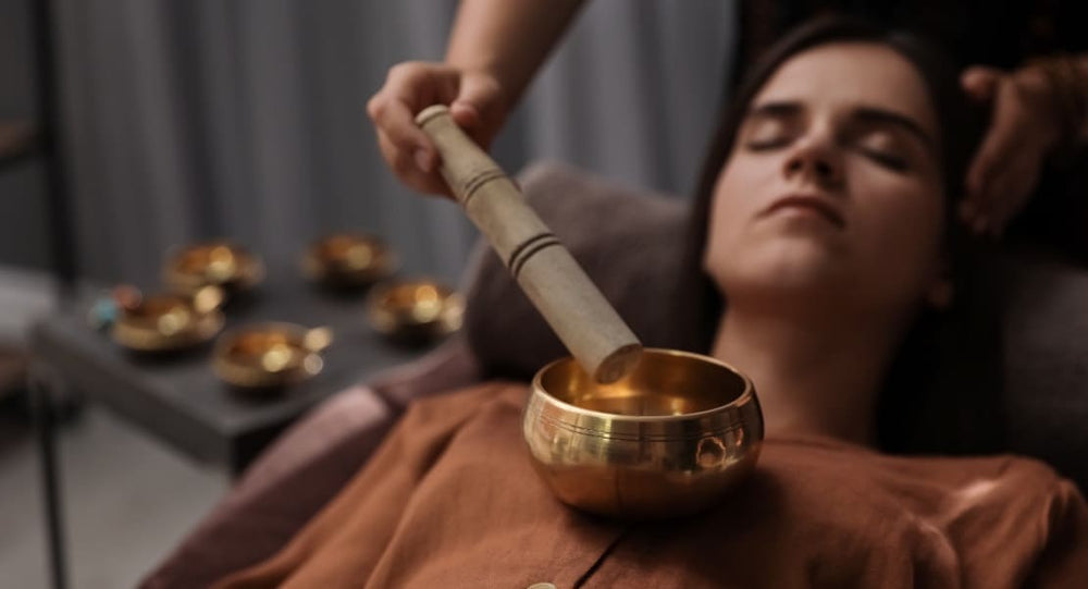 A woman enjoying a sound massage with a Tibetan singing bowl